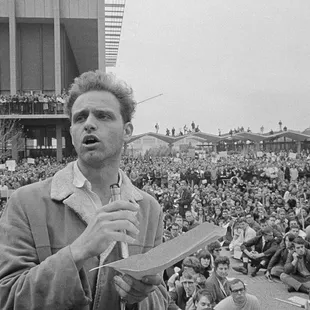 Mario Savio stands atop a Berkeley police car speaking to the masses on freedom of speech at Sproul Plaza.
