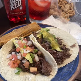 All meat Barbacoa tacos on corn tortillas with avocado and green salsa on one, pico de gallo on another.