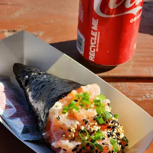 a sushi roll and a soda on a picnic table