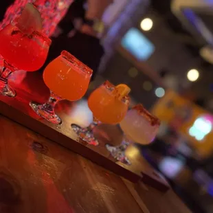 a row of cocktails on a bar