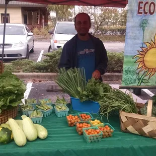 a man standing in front of a table of vegetables