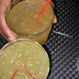 two people holding drinks with straws