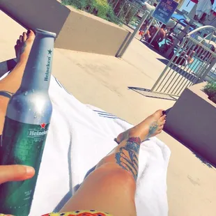 a woman laying on a towel with a beer in her hand