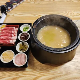 a pot of soup and bowls of meat