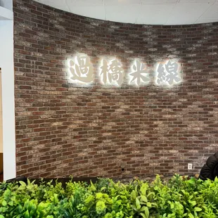 a man sitting at a table in front of a brick wall