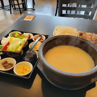 a hot pot of soup and bowls of soup