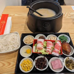 a pot of soup and bowls of noodles