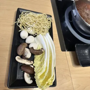 a plate of noodles, mushrooms, cabbage, and mushrooms