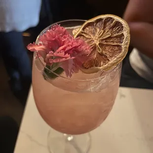 a pink cocktail with orange slices and flowers