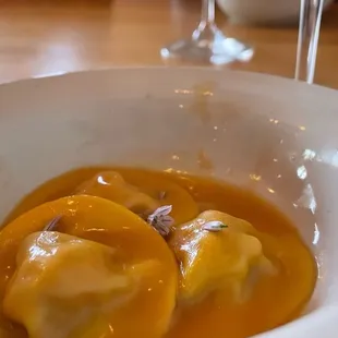 a bowl of ravieroli and two glasses of wine