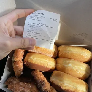 a hand holding a box of doughnuts