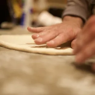 a person rolling out dough on a counter