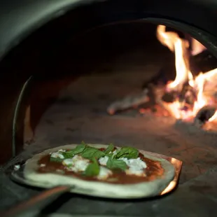 a pizza being cooked in a brick oven