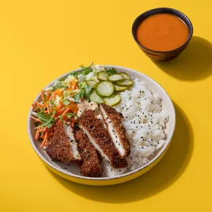 a bowl of rice, chicken, cucumbers, and sauce