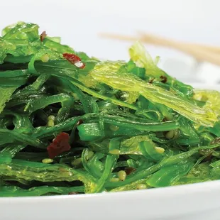 a bowl of seaweed with chopsticks