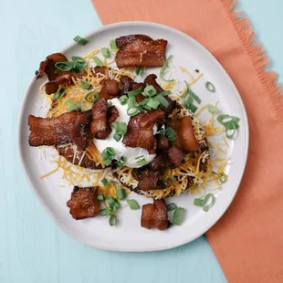 a plate of tater tots with bacon and cheese