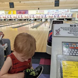 a young boy holding a bowling shoe