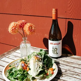 a plate of salad and a bottle of wine