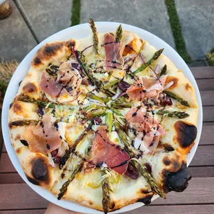 a pizza topped with asparagus and prosciutto