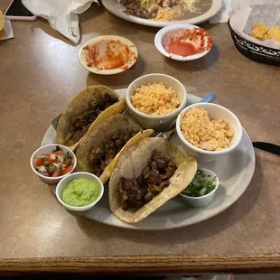 a plate of tacos, rice, beans, and guacamole