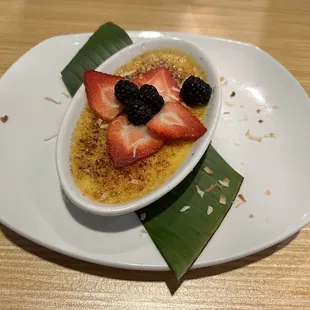 a bowl of creme with strawberries and blackberries