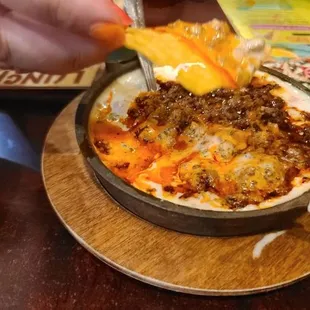 a person dipping cheese into a dish