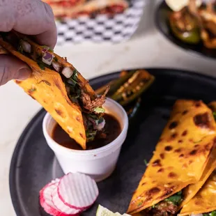 a hand dipping a tortilla