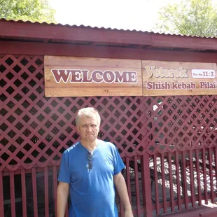 a man standing in front of a welcome sign