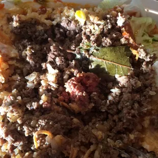 Piece of raw chunky ground beef and a bay leaf in the chimichanga.