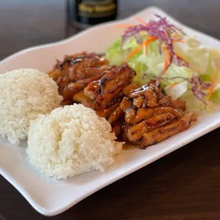 a plate of rice, meat and salad