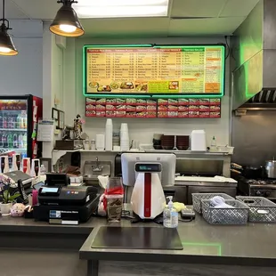 a restaurant counter with a menu on the wall
