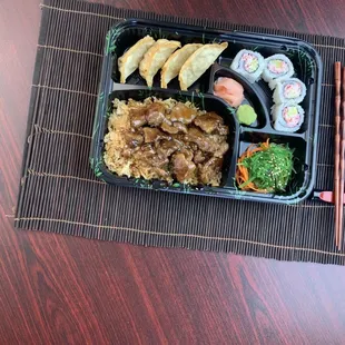 a meal in a plastic container with chopsticks