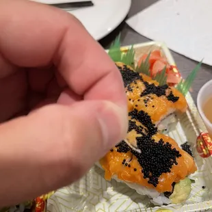 a hand holding a piece of sushi