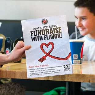 a boy holding a fundraiser flyer
