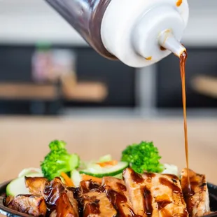 a hand drizzing sauce over a dish