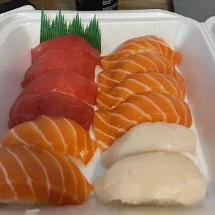 a variety of sushi in a styrofoam container