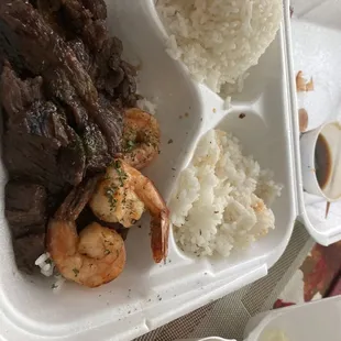 a tray of food with rice, meat, and vegetables