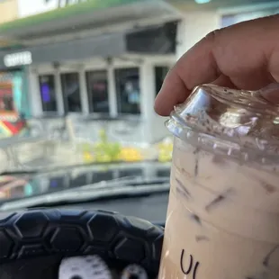 a hand holding a cup of iced coffee