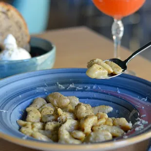 a person holding a spoon over a bowl of pasta