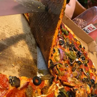 Black, charred crust on Deluxe pizza