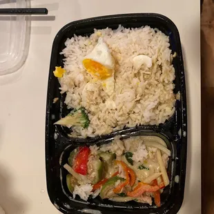 rice and vegetables in a plastic container with chopsticks