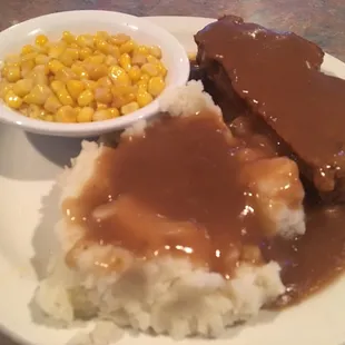 a plate of food with gravy, mashed potatoes, corn and gravy