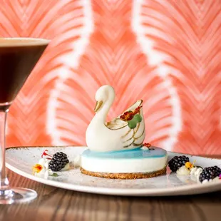 A white chocolate elegant swan filled with a Florida key lime mousse, atop of a mirror glazed vanilla bean cheesecake.