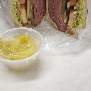 Pastrami on light rye sandwich, mild peppers on the side