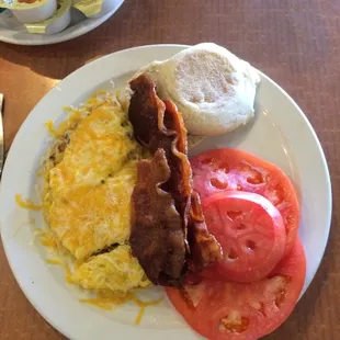 Meat lovers omelette with sliced tomato and English muffin.