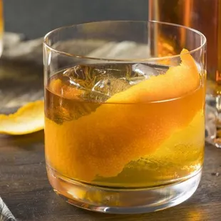 a glass of whiskey with an orange peel