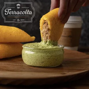 a hand dipping a piece of guacamole into a small bowl