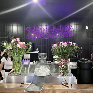 a woman standing in front of a counter with vases of flowers