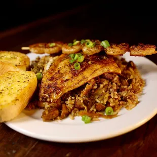 Blackened Redfish fillet, paired with a skewer of juicy grilled shrimp, all drizzled with a zesty lemon and garlic butter. Served over a hea