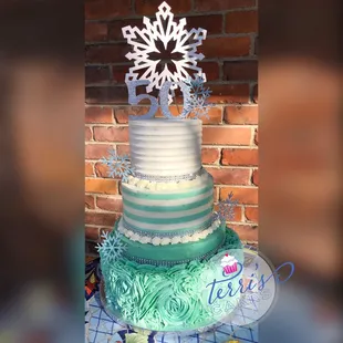 a three tiered cake decorated with frosting and snowflakes